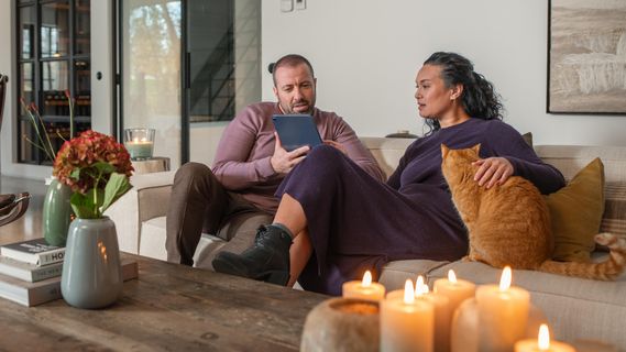 Character - Ein Mann und eine Frau auf einem Sofa schauen sich etwas auf einem Tablet an.