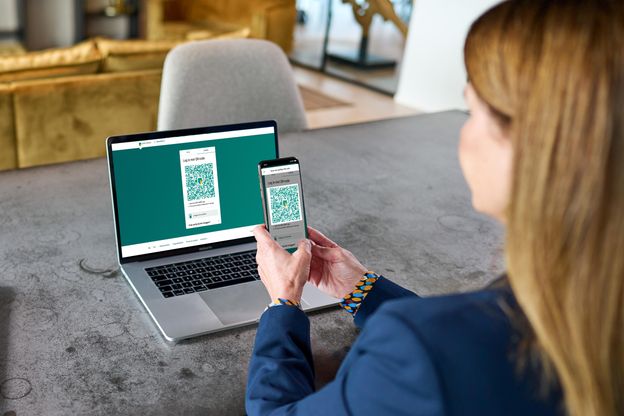 Woman aims mobile phone’s camera at the QR code on the Internet Banking login screen.