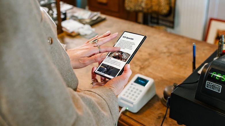 Persoon houdt een telefoon vast met op het scherm de pagina van ICS Specials.