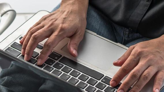 Hände, die auf einer Laptoptastatur tippen.