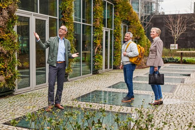 Drie personen aanschouwen in de buitenlucht een gebouw