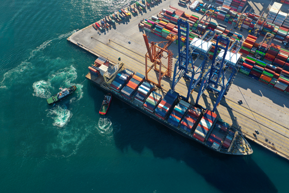 Un porte-conteneurs en cours de chargement et de déchargement dans un port, photographié depuis les airs.