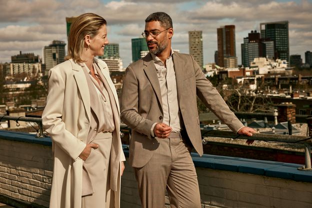 Twee personen staan met elkaar te praten met op de achtergrond de skyline van een stad